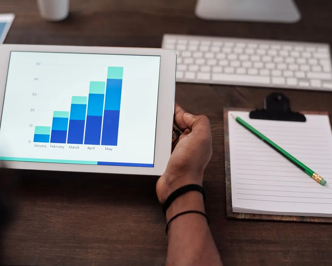 Tablet showing a conversion report bar chart beside a notepad